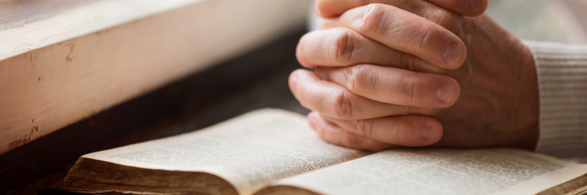 Hands folded over bible