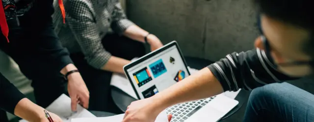 People reviewing papers around a computer