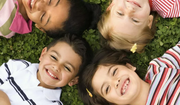 Children lying in clover with heads together. Vertically framed shot.